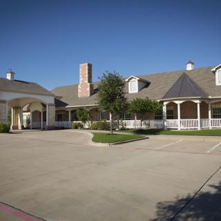 A large residential building with a spacious driveway and clear blue sky.