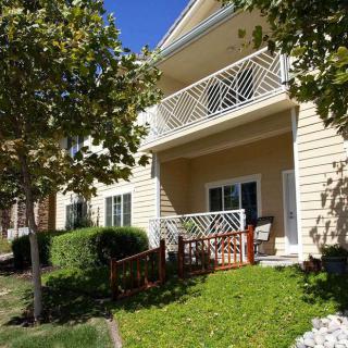 A sunny day view of a residential house with balconies and a small front yard.