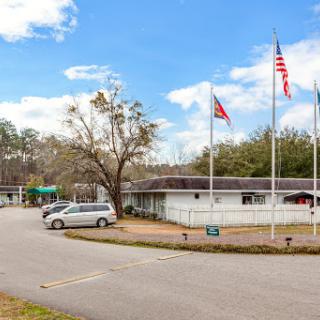 A view of a building with multiple flags in front, set against a backdrop of blue skies and trees.