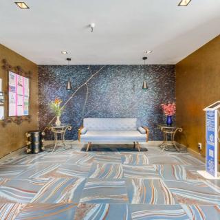 A modern living room featuring a stylish sofa, artistic wall decor, patterned carpet, and decorative flower vases.