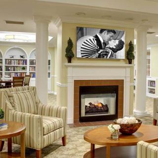 A cozy living room featuring a fireplace, artwork above the mantel, comfortable seating, and built-in bookshelves.