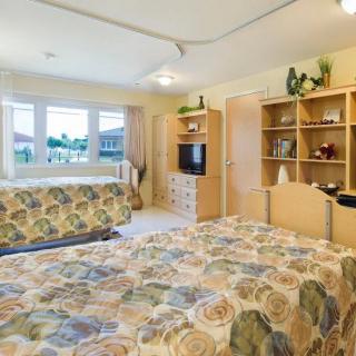 A cozy bedroom featuring twin beds, decorative shelves, and a television.