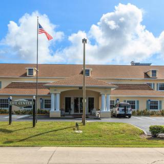 A large building with an American flag in front, set against a partly cloudy sky.