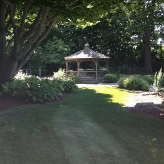 A serene garden with a gazebo surrounded by lush trees and greenery.