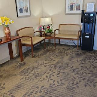 A cozy waiting area featuring comfortable chairs, a small table, and a water cooler.