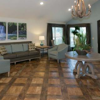 A stylish living room with wooden flooring, featuring a sofa set, armchairs, a coffee table, and a chandelier.