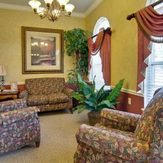A cozy living room with patterned furniture, a chandelier, and elegant curtains.