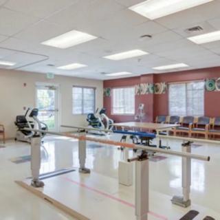 A rehabilitation room equipped with exercise machines and therapy bars.