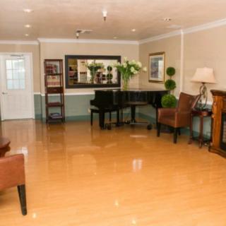 A well-decorated room featuring a grand piano, chairs, and elegant furnishings.