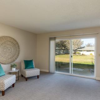 A bright and airy living room featuring two chairs and a large sliding glass door leading to an outdoor space.