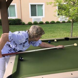 A person is playing billiards on an outdoor pool table.