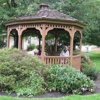 A wooden gazebo nestled in a lush garden setting.