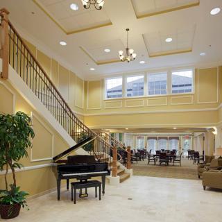 A luxurious living room with a grand piano and elegant staircase.