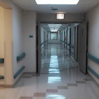 An empty and clean hospital corridor with open doors and bright lighting.