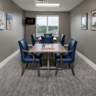 A small conference room with a table and four chairs, featuring wall art and a window.