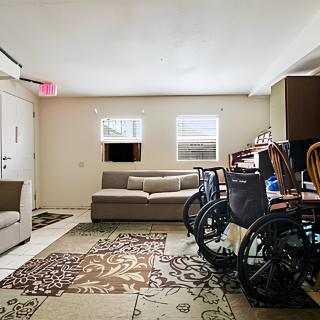 A cozy living room with sofas, a wheelchair, and patterned carpets.