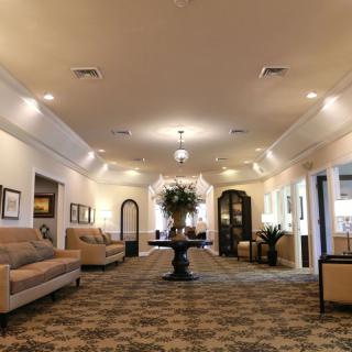 A spacious, elegantly decorated lobby with sofas, a central table with floral arrangement, and soft lighting.