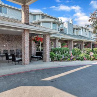 Exterior view of a residential building with outdoor seating and landscaped surroundings.