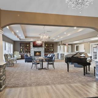 A luxurious and spacious lounge featuring a grand piano, chandelier, and cozy seating by the fireplace.