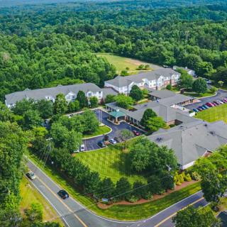 Aerial view of a large building complex surrounded by lush greenery and roads.