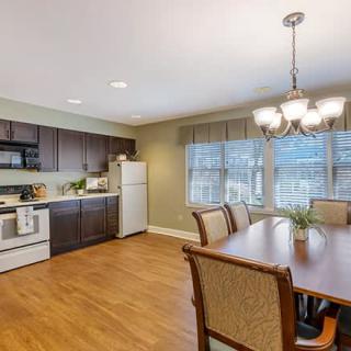 A modern kitchen and dining area featuring wooden flooring, sleek appliances, and elegant lighting.