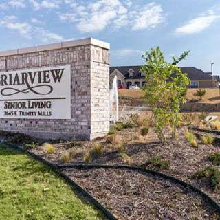 A senior living community sign with well-maintained landscaping in front of a residential building.