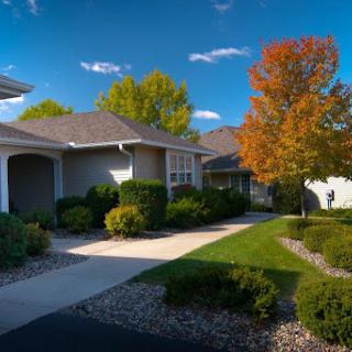 A picturesque neighborhood showcasing charming houses surrounded by vibrant autumn foliage and a clear blue sky.
