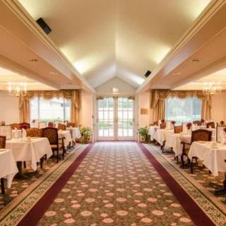 An elegant restaurant dining room with neatly arranged tables and chairs, large windows, and a patterned carpet.