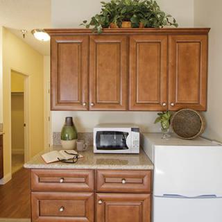 A kitchen setup with wooden cabinets, a microwave, and a refrigerator.