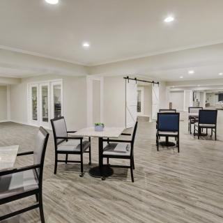 A spacious and modern dining area with tables and chairs, featuring a hardwood floor and bright lighting.