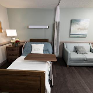 A modern hospital room equipped with a patient bed, a comfortable sofa, and tasteful decor.