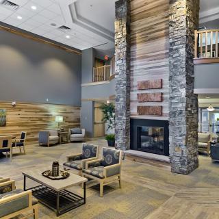 A modern hotel lobby featuring a cozy seating area and a large stone fireplace.