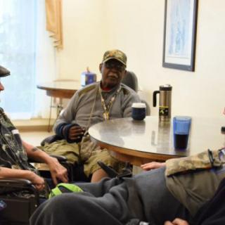 A group of people sit around a table engaged in discussion.