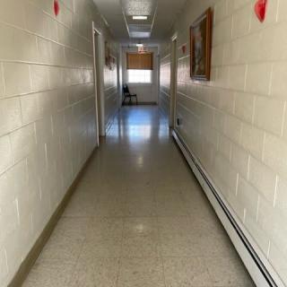 A long, narrow hallway with a shiny floor and doors on either side.