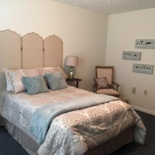 A cozy and well-decorated bedroom with a bed, chair, and lamp.