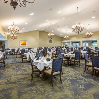 A spacious and elegantly decorated dining room with neatly arranged tables and chandeliers.