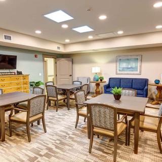 A spacious and well-lit lounge area with tables and chairs, a sofa, and a television.