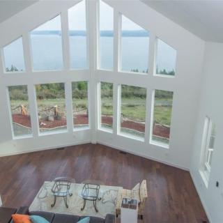 A modern living room with large windows offering a scenic lake view.