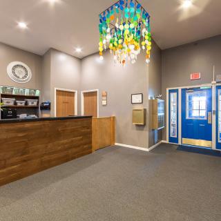 A cozy reception area with a wooden desk and a colorful chandelier.