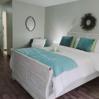A modern bedroom with stylish decor, featuring a neatly made bed with teal and white bedding and pillows.