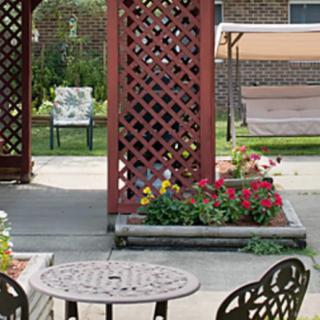 A cozy garden patio featuring a decorative lattice, colorful flowers, and outdoor furniture.