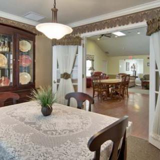 A cozy dining room with a lace-covered table and a china cabinet displaying decorative plates.