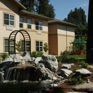 A landscaped garden with a small waterfall in front of a modern building.
