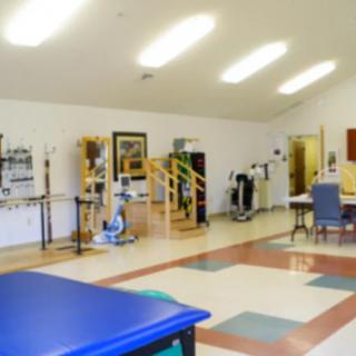 A spacious physical therapy room equipped with various exercise machines and rehabilitation tools.