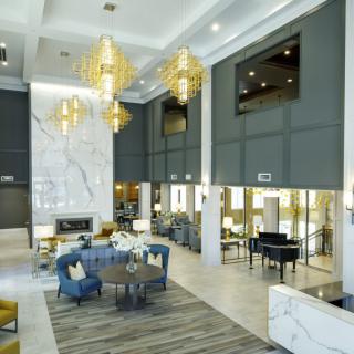 A luxurious and modern lobby featuring elegant chandeliers, plush seating, and a grand piano.