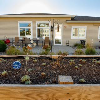 A backyard view with a patio, outdoor seating, and a landscaped garden featuring succulents.