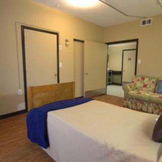 A cozy bedroom with a bed, sofa, and multiple doors.