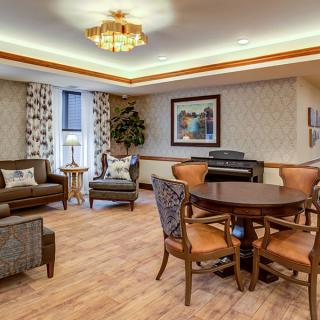 A cozy living room featuring comfortable seating, a dining table with chairs, and a piano against the wall.