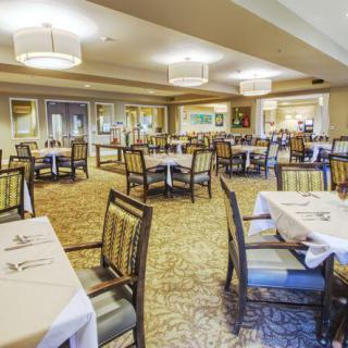 A spacious dining area with neatly arranged tables and chairs, featuring elegant lighting and decor.