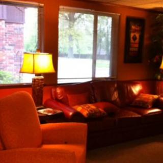 A cozy living room with a sofa, lamps, and large windows.